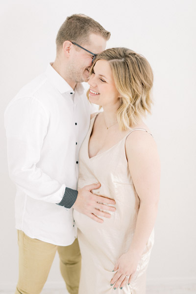 Zwangerschapsshoot boudoir in de studio met haarstyling, visagie en zwangerschapsjurken uit de client closet. Lichte, ontspannen zwanger en newborn fotoshoot. Fotograaf baby’s eerste jaar. Zwangerschapsfoto met partner