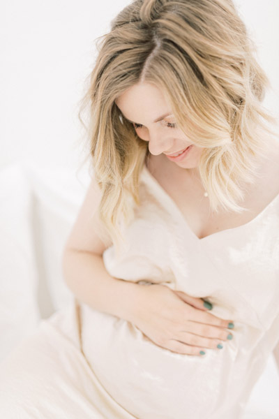 Zwangerschapsshoot boudoir in de studio met haarstyling, visagie en zwangerschapsjurken uit de client closet. Lichte, ontspannen zwanger en newborn fotoshoot. Fotograaf baby’s eerste jaar. Zwangerschapsfoto 32 weken zwanger